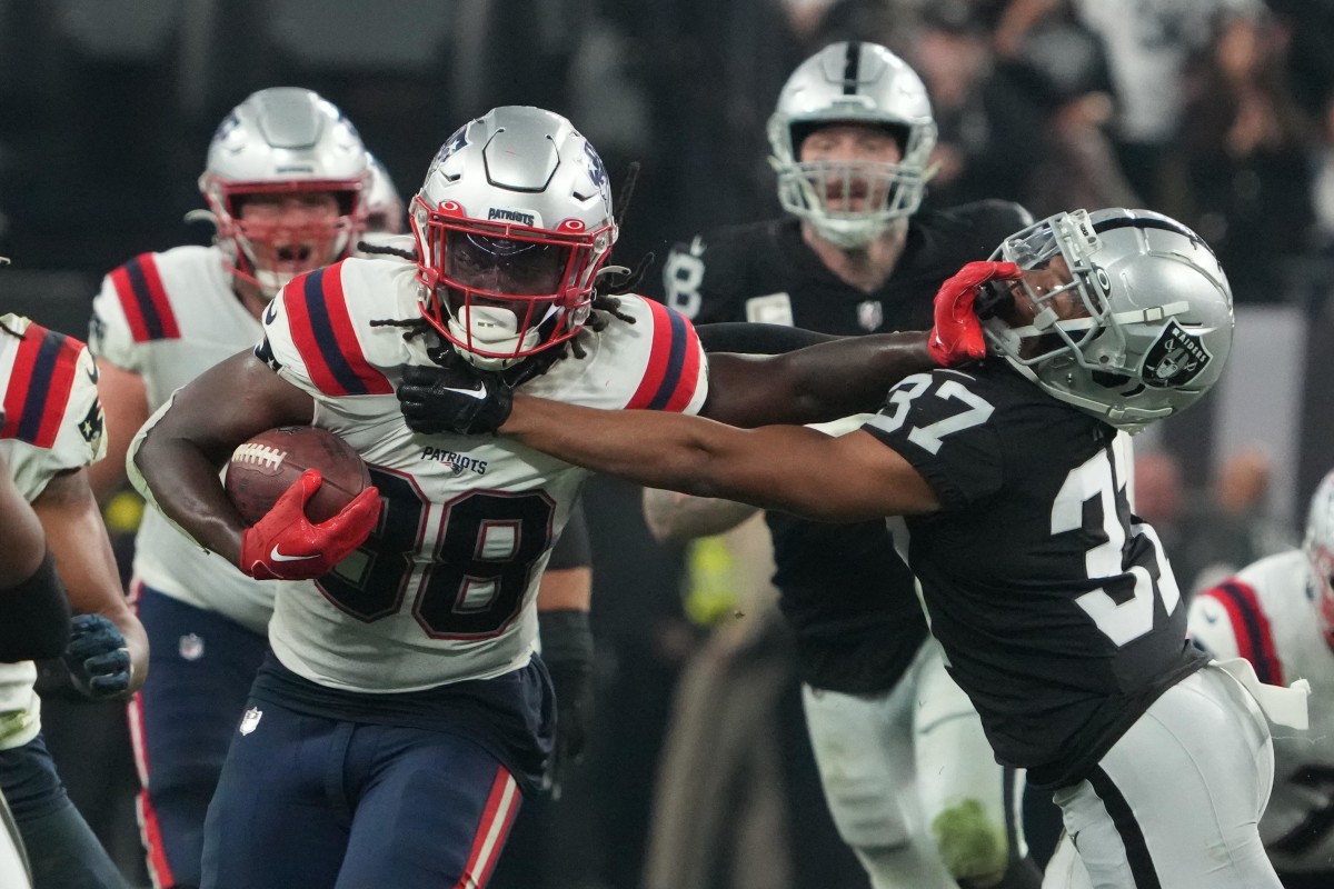 Patriots running back Rhamondre Stevenson stiff arms a Raiders defender.